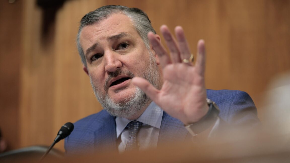 Sen. Ted Cruz holds up a hand and speaks while presiding over a Senate subcommittee hearing.