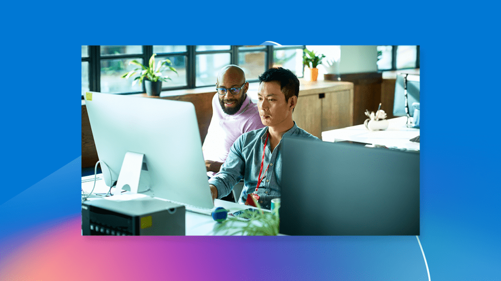 Two people working at a computer in an office.