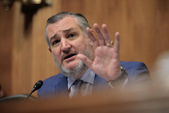 Sen. Ted Cruz holds up a hand and speaks while presiding over a Senate subcommittee hearing.