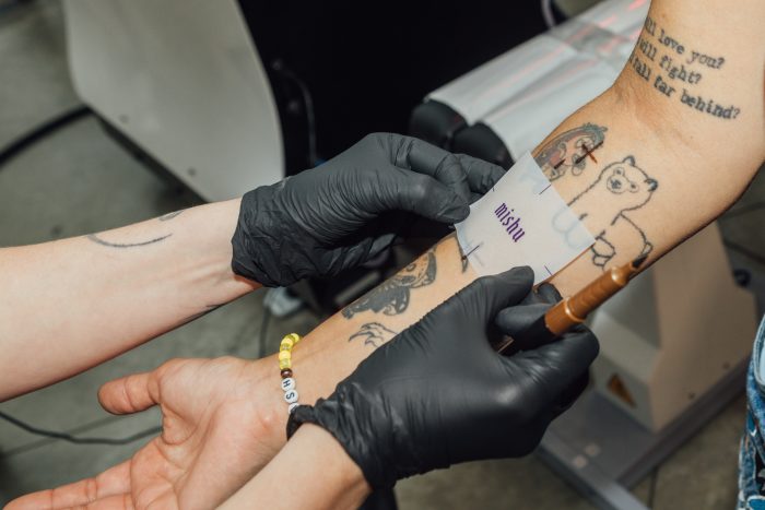 A tattoo artist placing a stencil on a customer's arm.