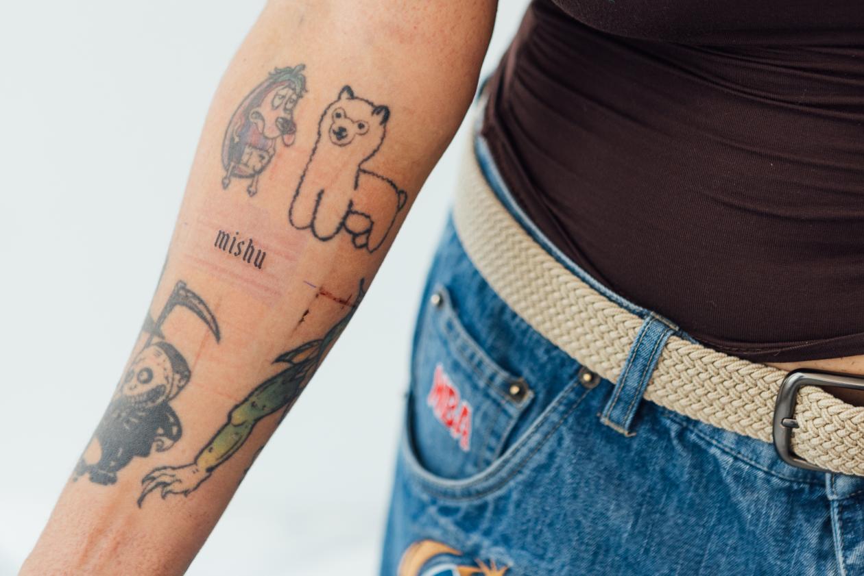 Person's arm with several tattoos, including an alpaca.